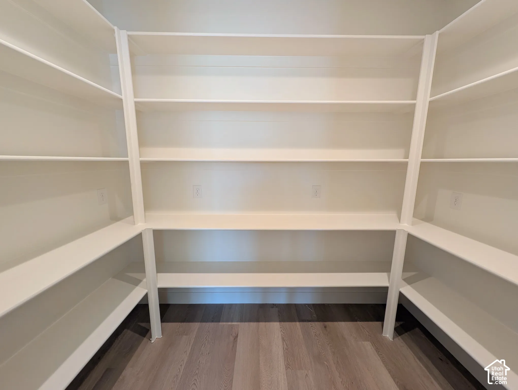 Extensive built-in shelving with multiple levels, U-shaped configuration, light wood-finish flooring, and light-toned walls