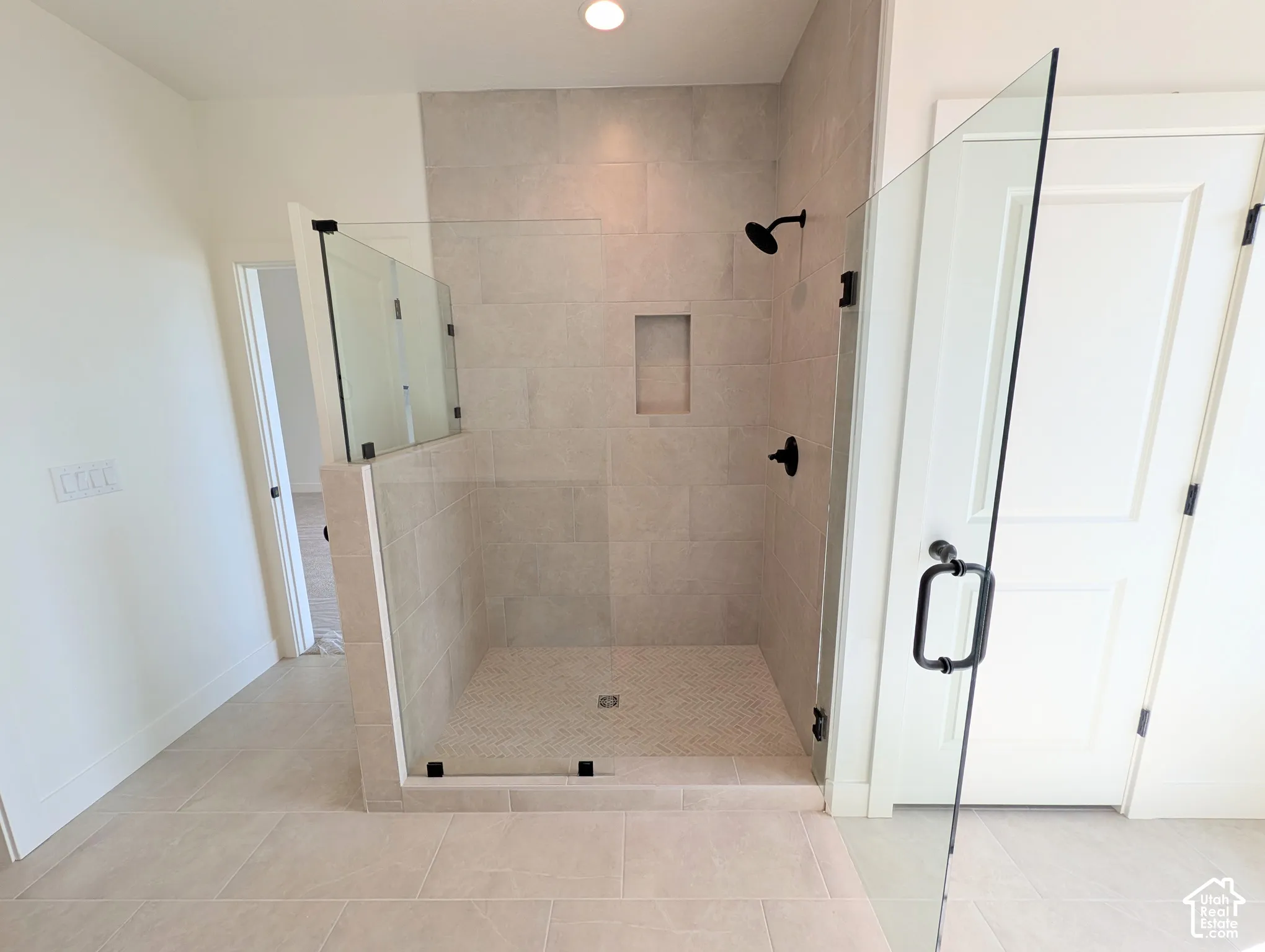 Walk-in shower with clear glass enclosure, a built-in shower niche, and matte black fixtures