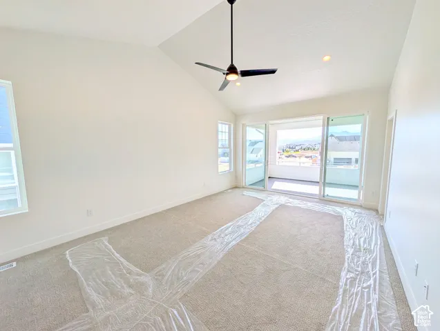 Primary bedroom with Vaulted ceiling, ceiling fan, recessed lighting, carpeted flooring, and sliding glass door access to a balcony