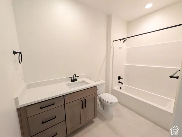 Contemporary bathroom featuring a wood-finish vanity with a light-colored countertop, recessed lighting, and a white tub and shower surround