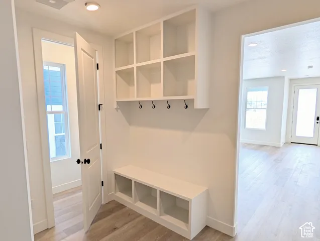 Entryway mudroom with built-in bench seating, integrated storage cubbies, and overhead shelving