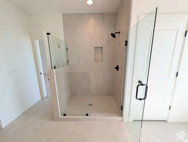 Walk-in shower with clear glass enclosure, a built-in shower niche, and matte black fixtures
