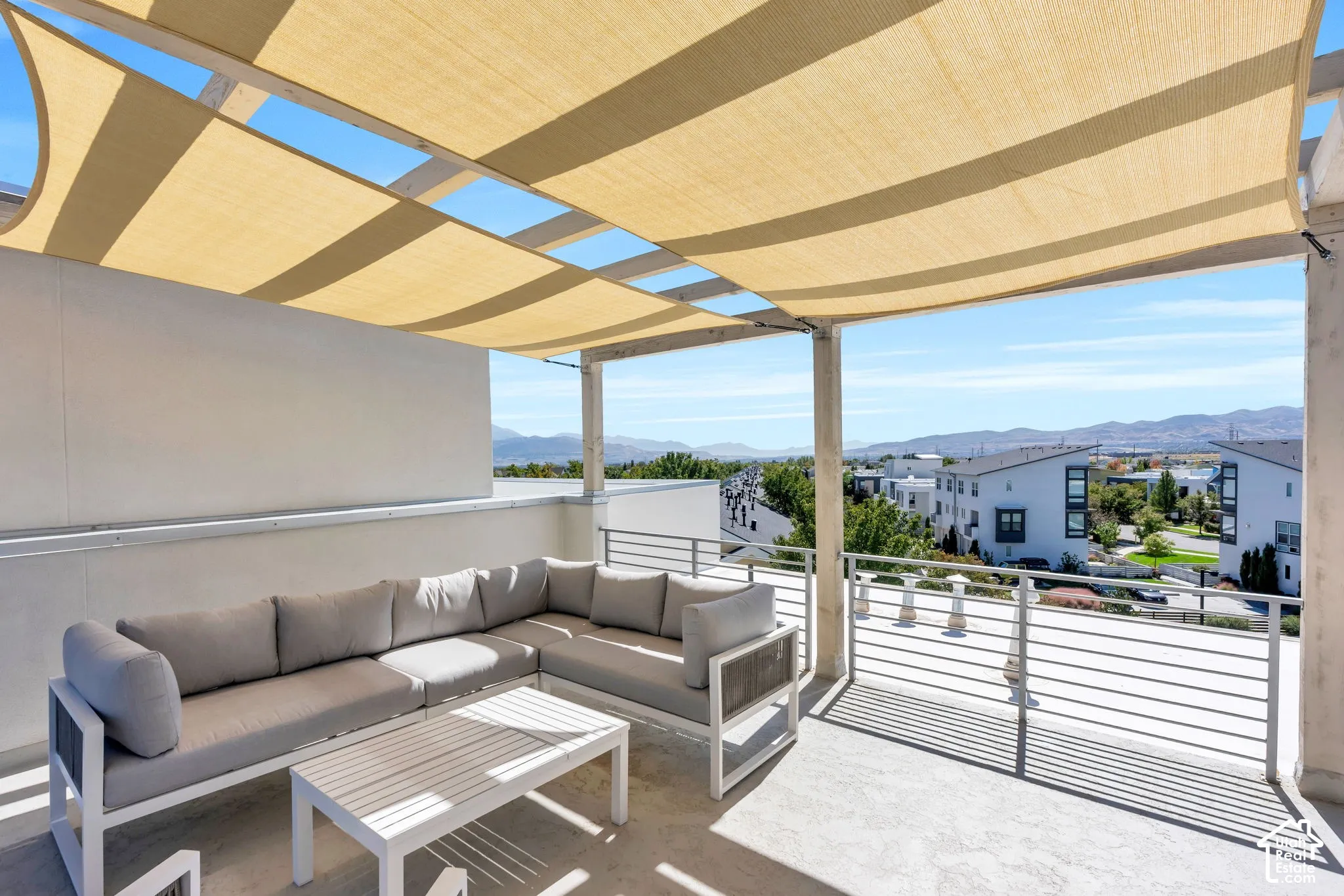 Rooftop deck featuring a slatted pergola with shade sails, concrete flooring, and metal railings
