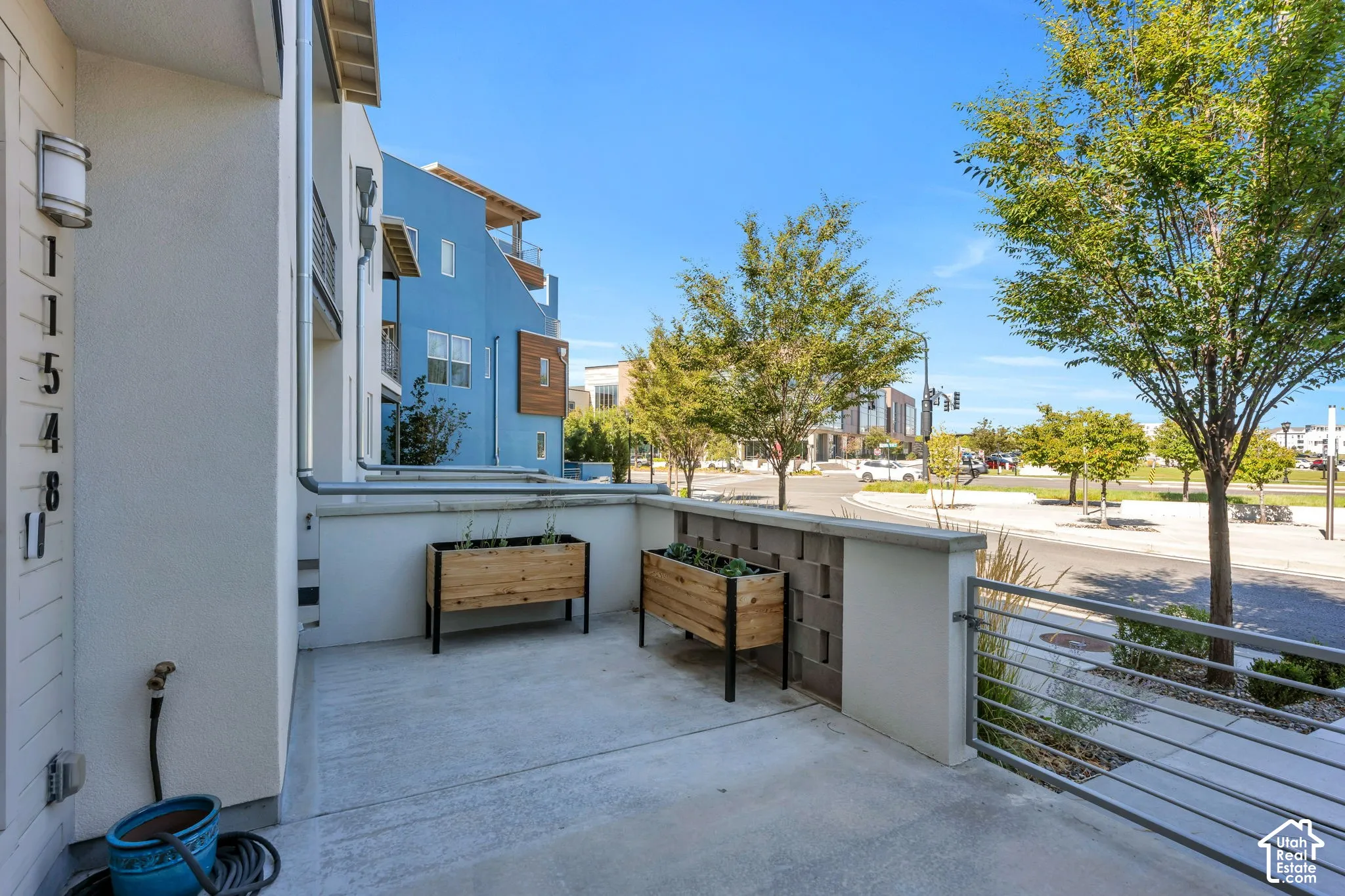 Concrete patio with modern wood planters, block wall accent, and metal railing