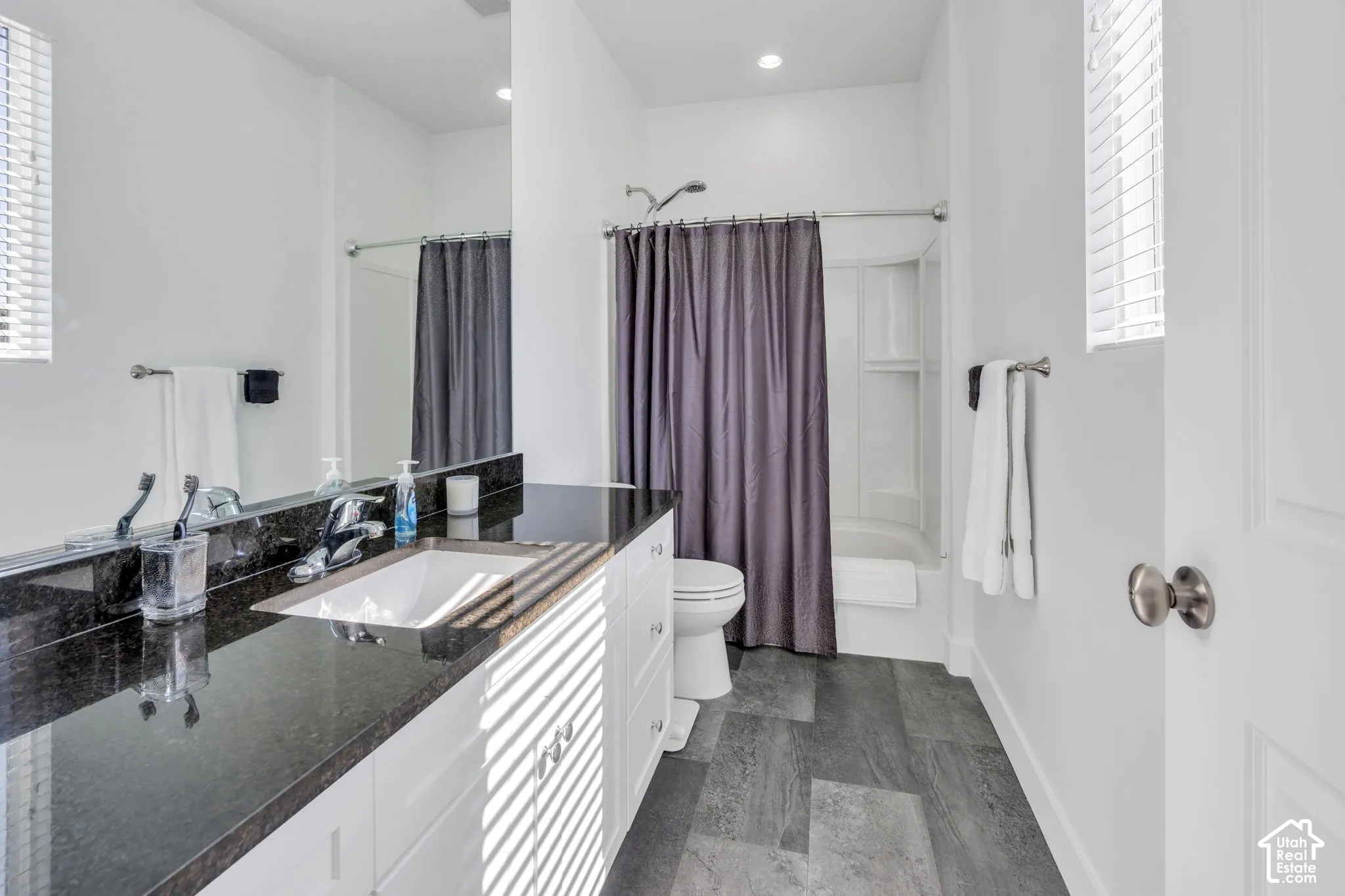 White shaker vanity with a dark countertop, undermount sink, and chrome faucet