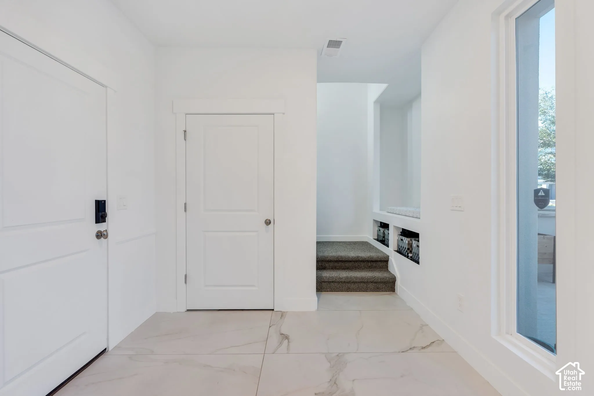 White panel doors with dark hardware, built-in bench seating with storage cubbies, and marble-look floor tiles