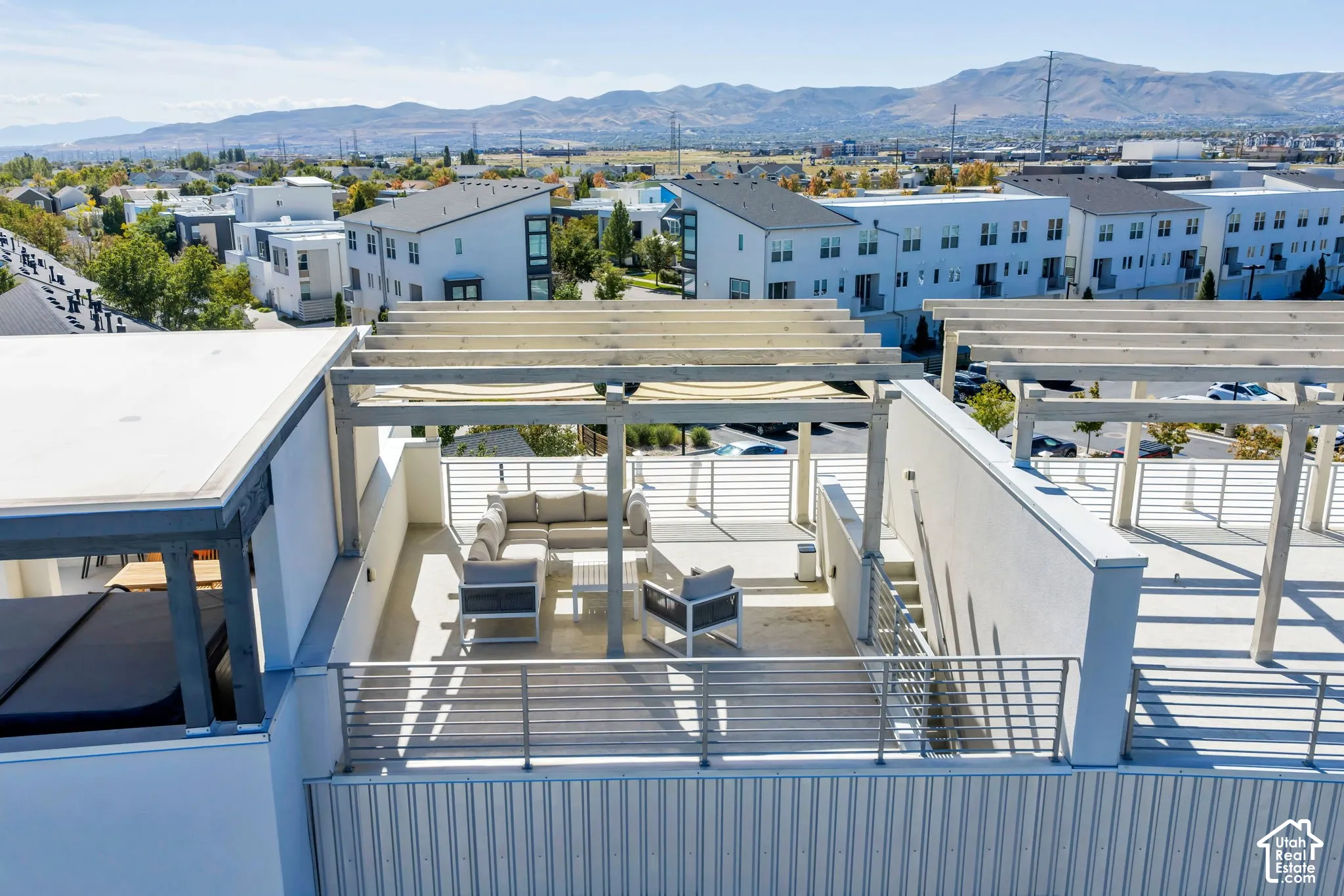 Rooftop patio with a pergola, metal railings, and mountain scenery