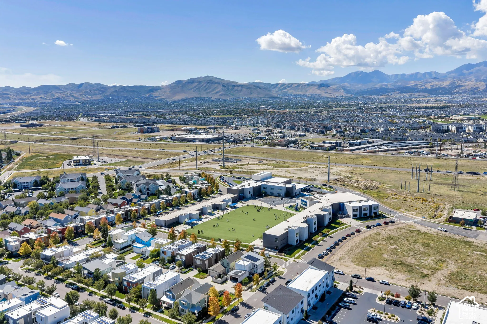 Aerial perspective showcasing a residential community with contemporary architecture, expansive green spaces, and mountain scenery