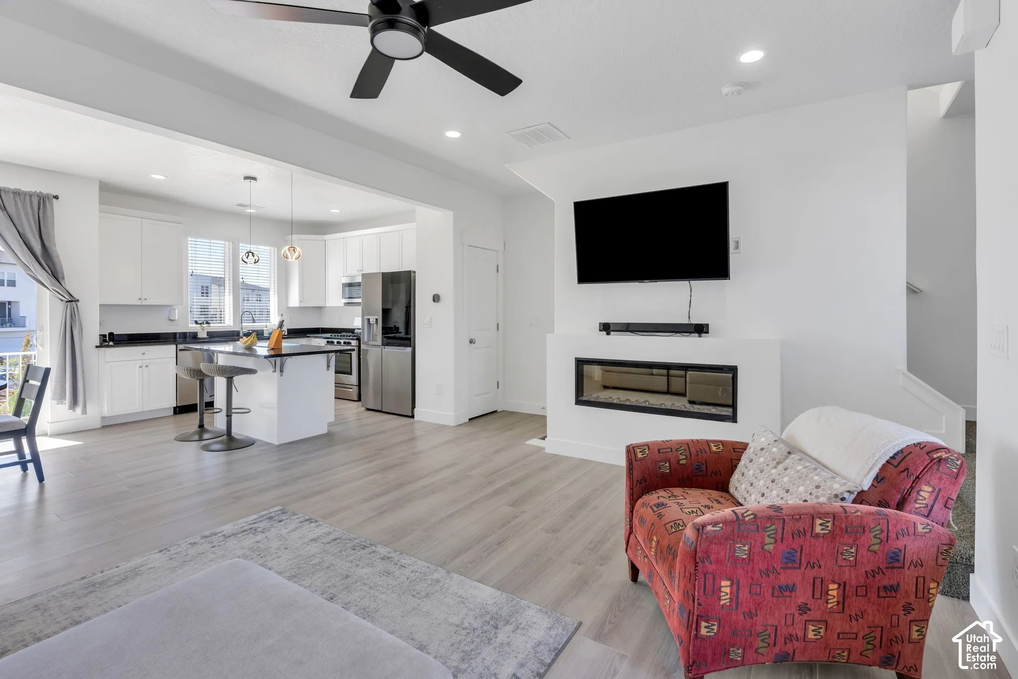 Open-concept living space with wood-finish flooring, a contemporary built-in fireplace, and a ceiling fan