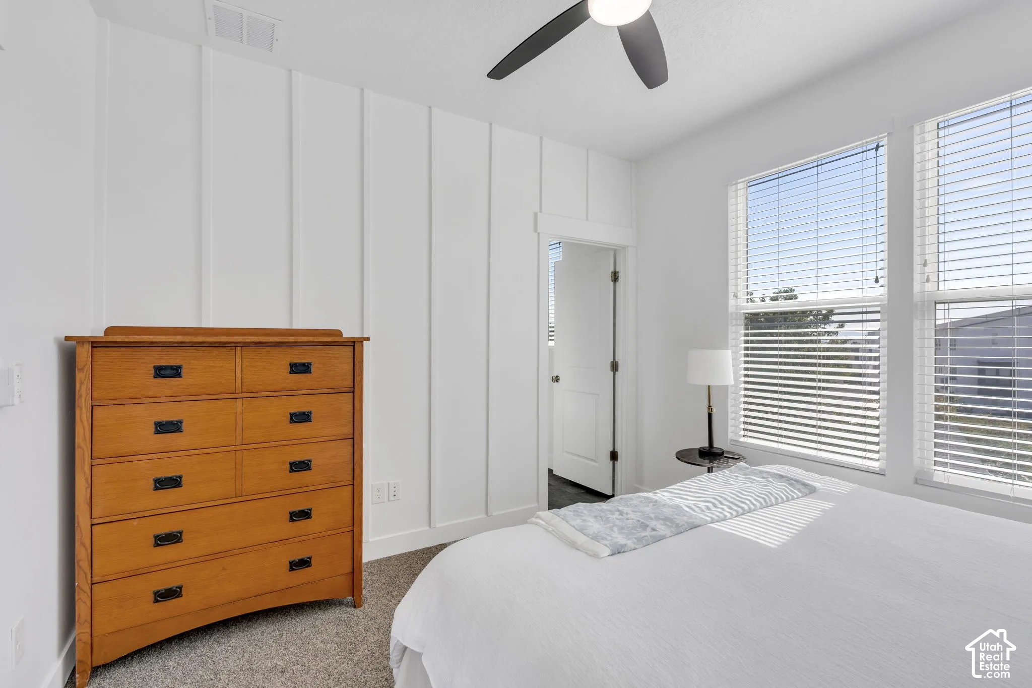 Board and batten accent wall, dual windows with blinds, ceiling fan with integrated lighting, and carpeted flooring
