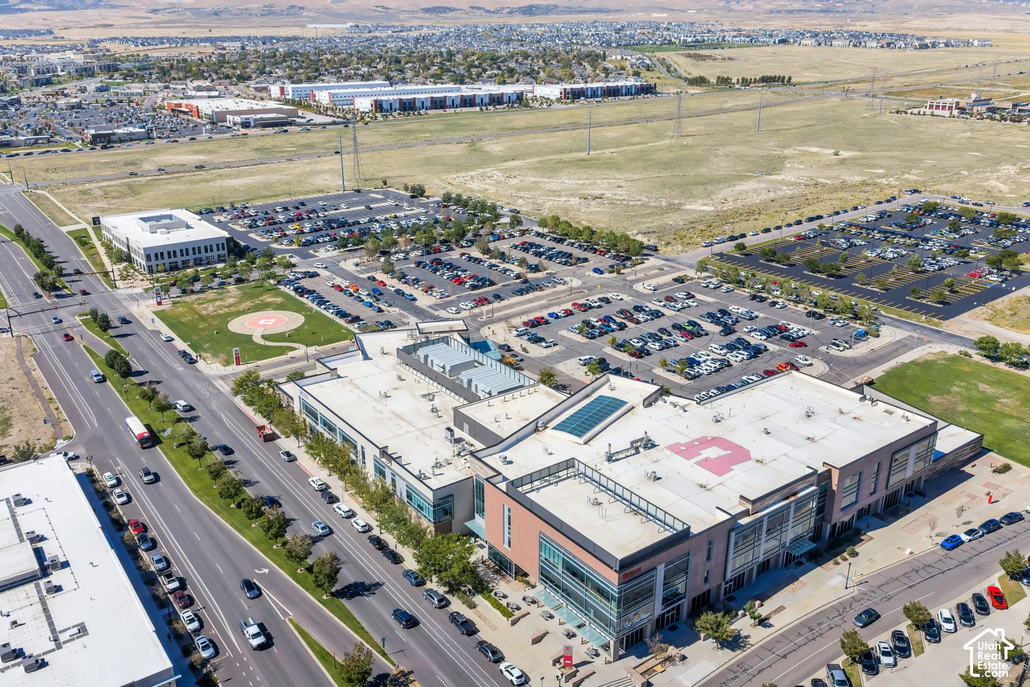 Expansive commercial complex featuring multiple buildings, extensive surface parking, direct road frontage, and adjacent undeveloped land