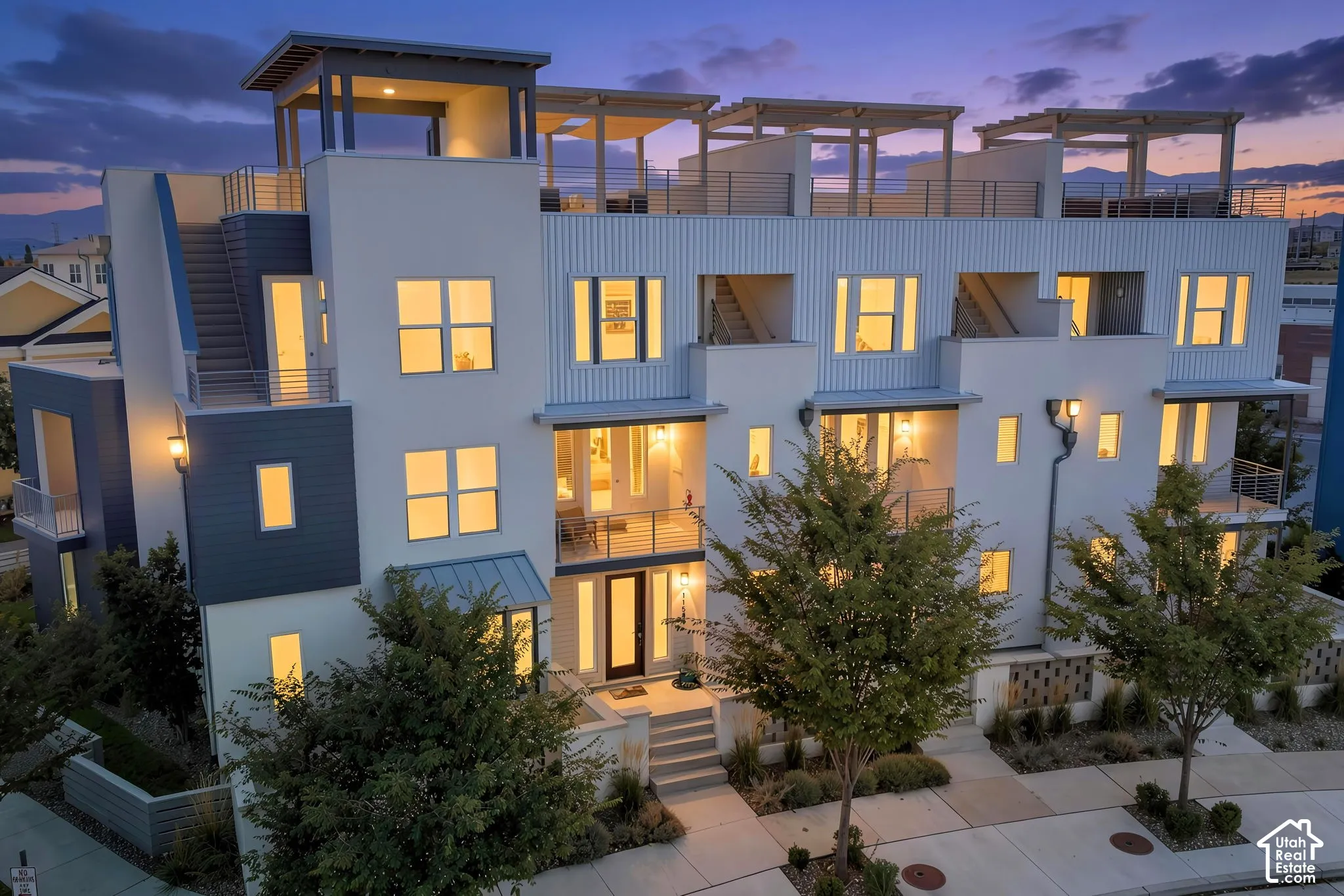 Contemporary multi-level exterior with multiple balconies, rooftop deck with pergolas, and a combination of smooth and corrugated panel siding