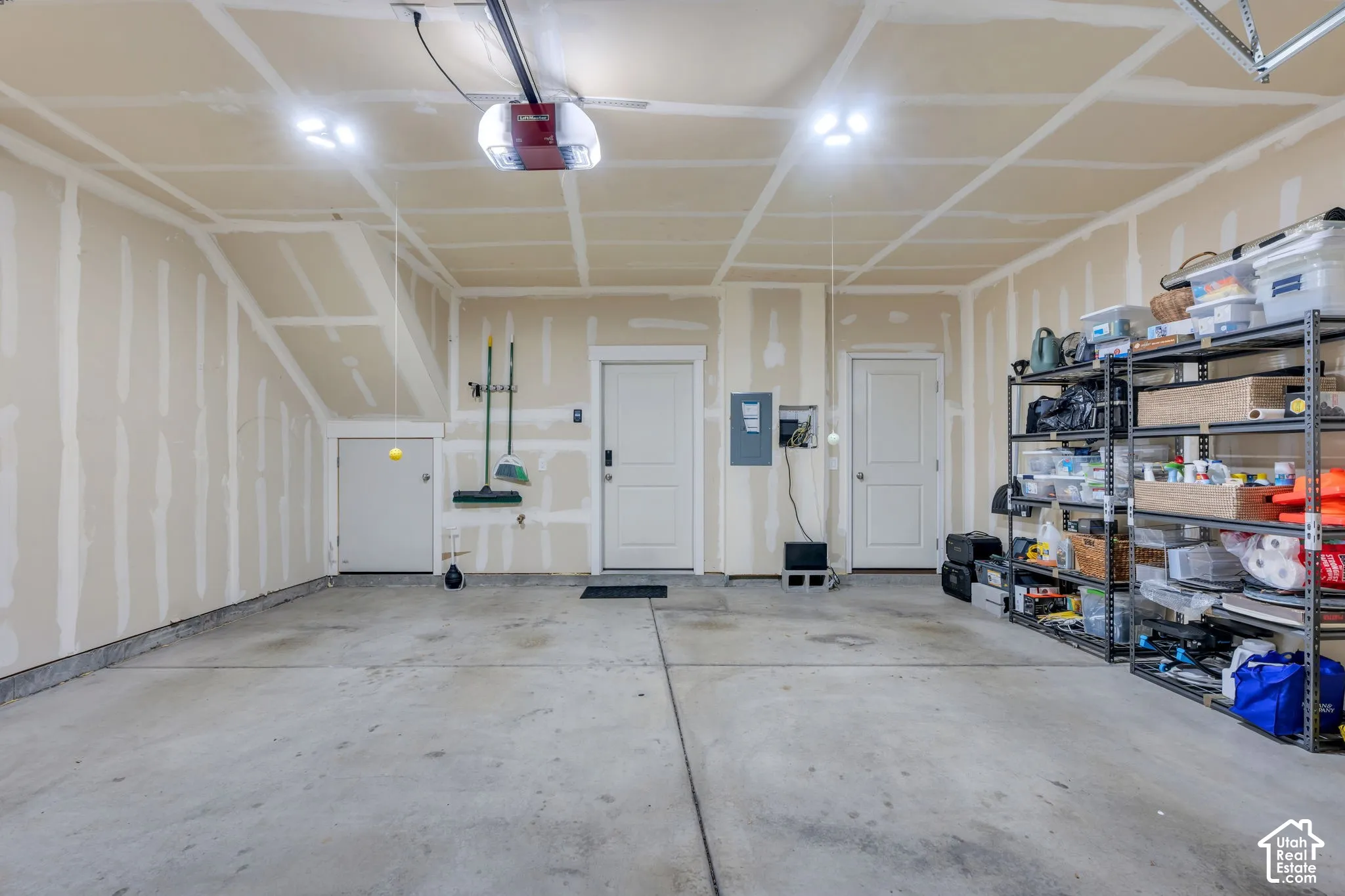 Attached garage with concrete flooring, two access doors, and overhead lighting