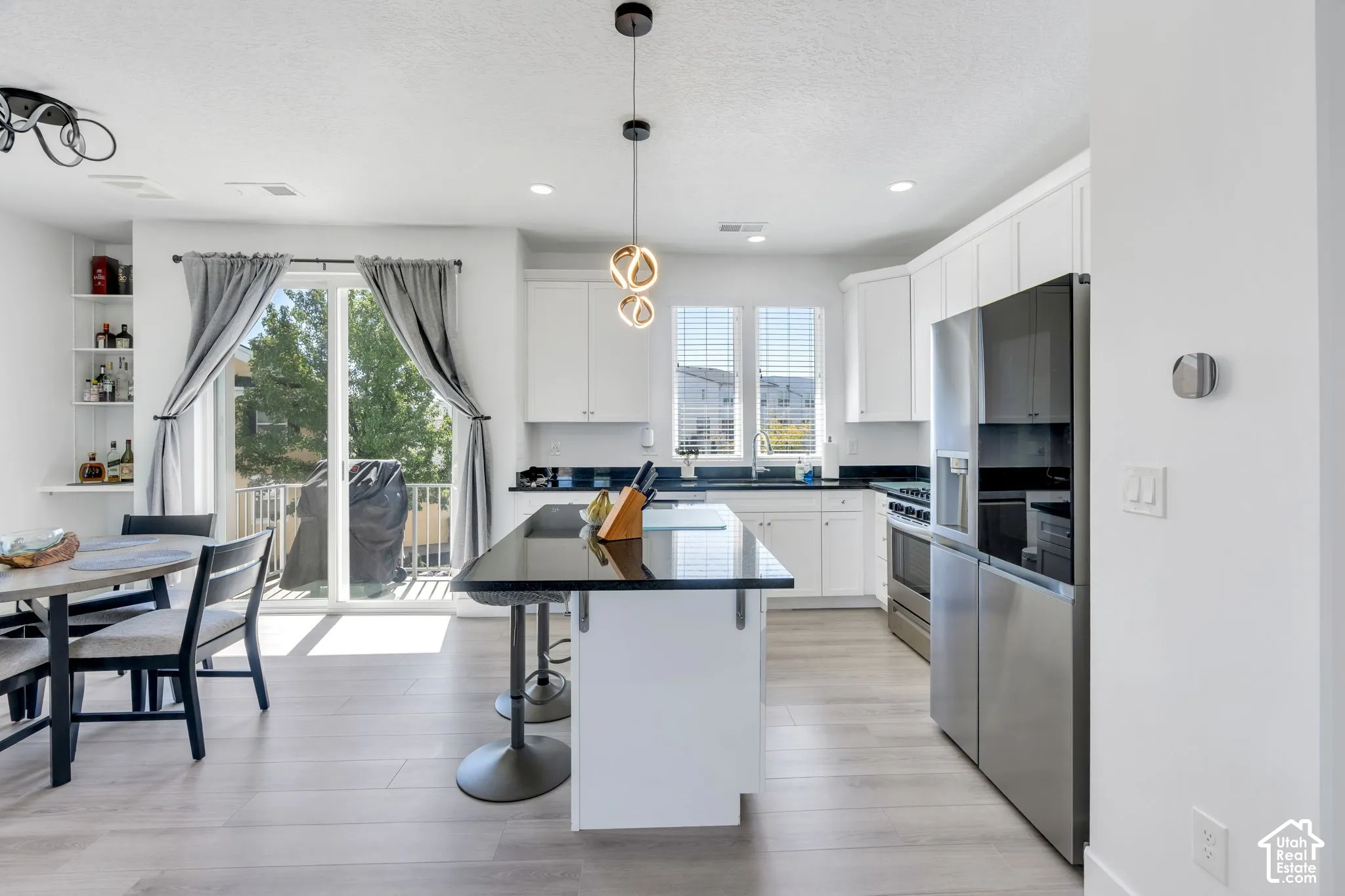 Kitchen featuring white cabinetry, dark countertops, stainless steel appliances, and wood-finish flooring