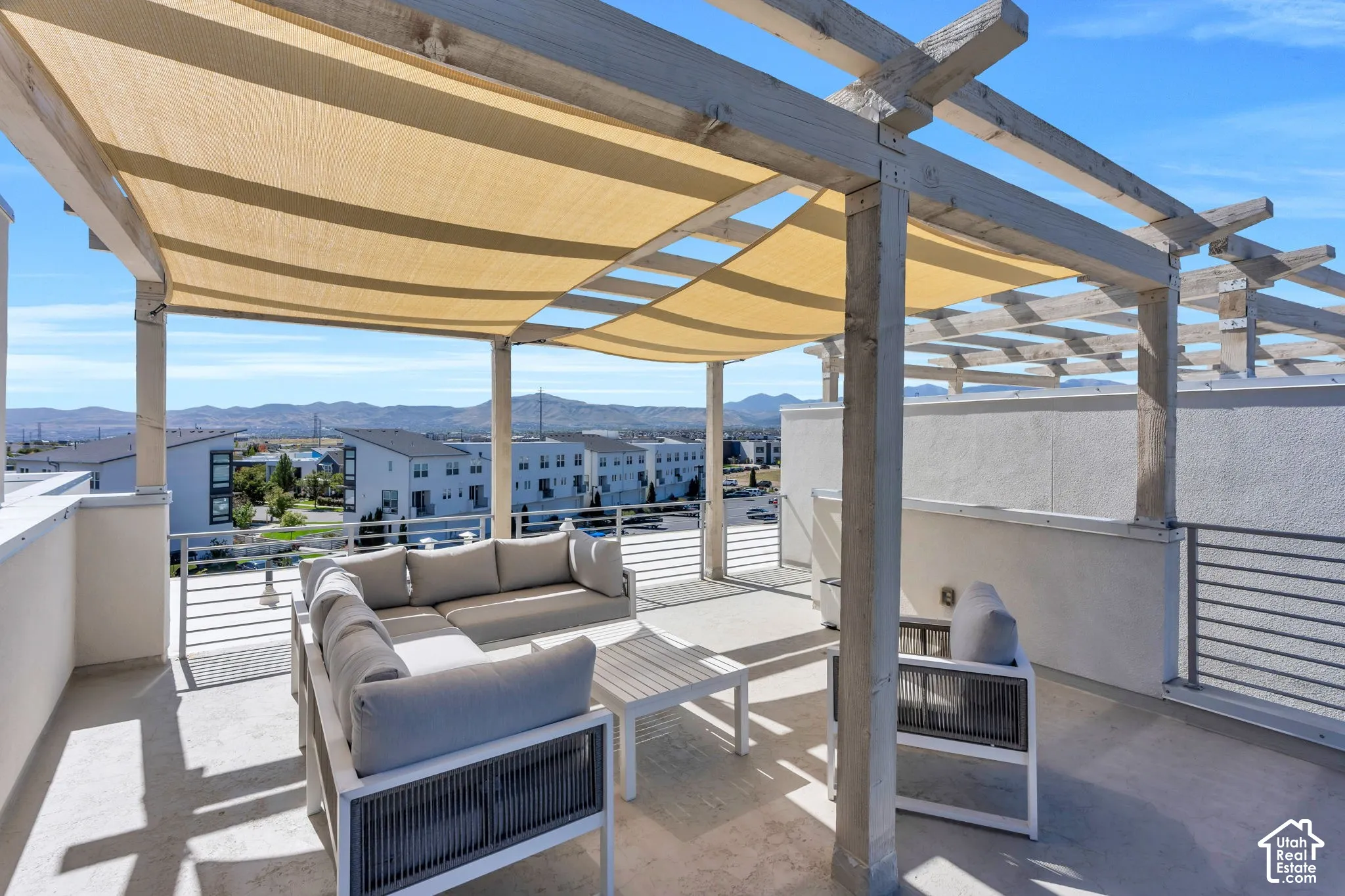 Rooftop deck featuring a wooden pergola, shade canopy, concrete flooring, and metal railings