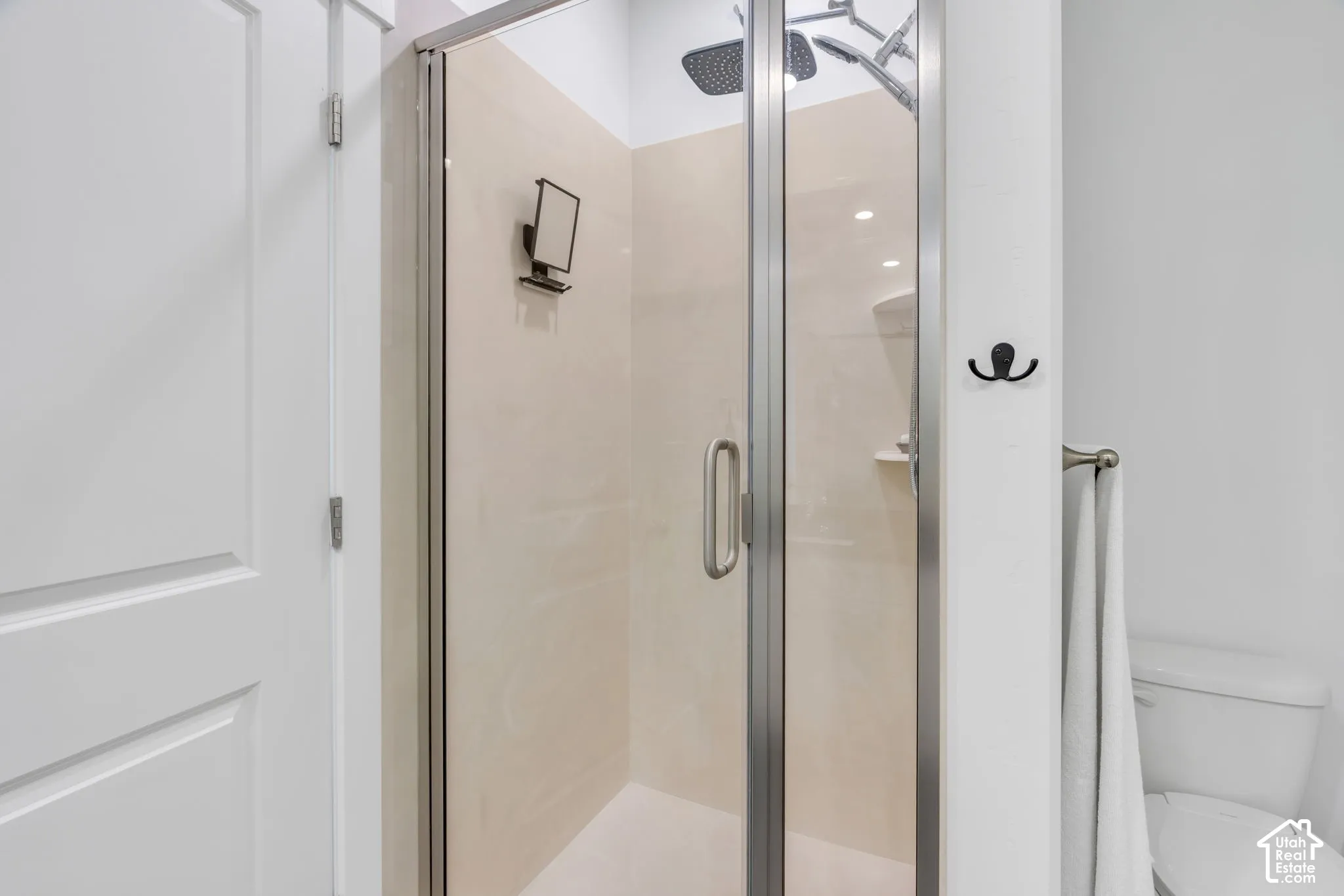 Glass-enclosed shower with a brushed nickel frame, rain shower head, and light-toned tile surround