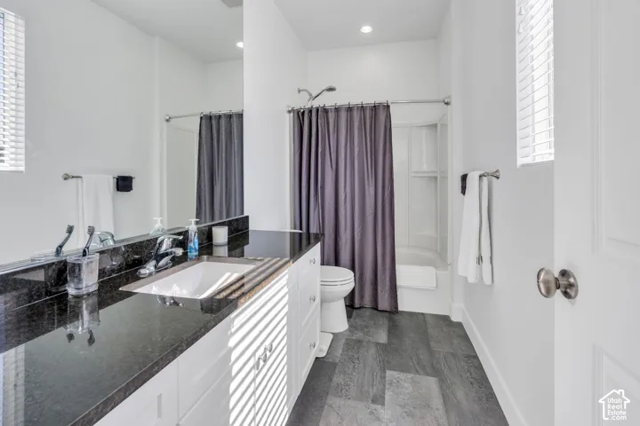 White shaker vanity with a dark countertop, undermount sink, and chrome faucet