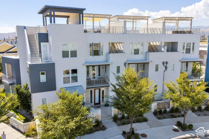 Modern multi-story facade featuring multiple balconies and a rooftop deck with pergola structures