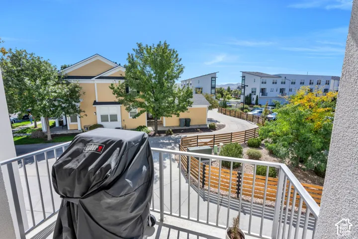 Balcony with metal railing overlooking landscaped grounds and residential buildings