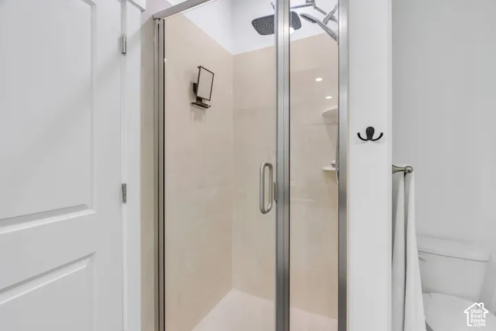 Glass-enclosed shower with a brushed nickel frame, rain shower head, and light-toned tile surround