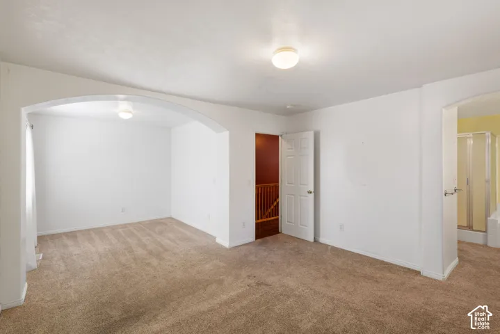 Expansive room featuring neutral-toned carpeting, an arched doorway, and recessed ceiling lighting