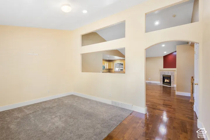 Arched entryway with wood-finish flooring, recessed lighting, and a gas fireplace with a tile surround