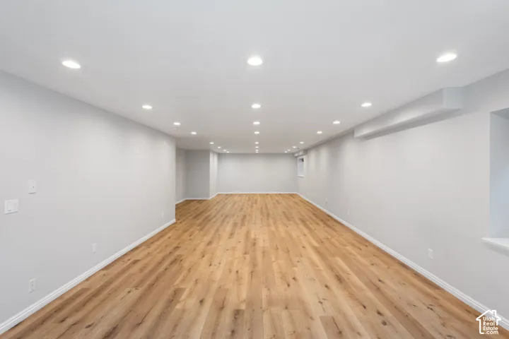 Expansive open-concept room featuring light-toned wood-finish flooring, recessed lighting, and neutral wall tones