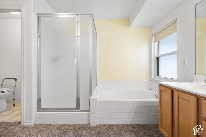 Integrated shower and bathtub combination with a privacy glass enclosure, light wood-finish vanity, and a window for natural illumination