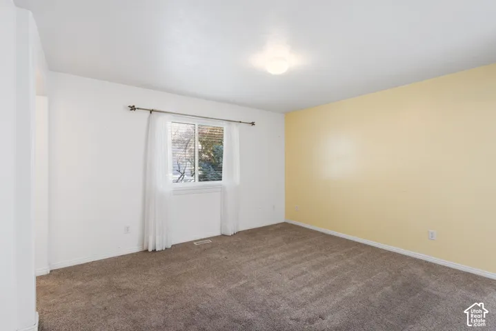 Carpeted flooring, single pane window, arched doorway, and overhead lighting