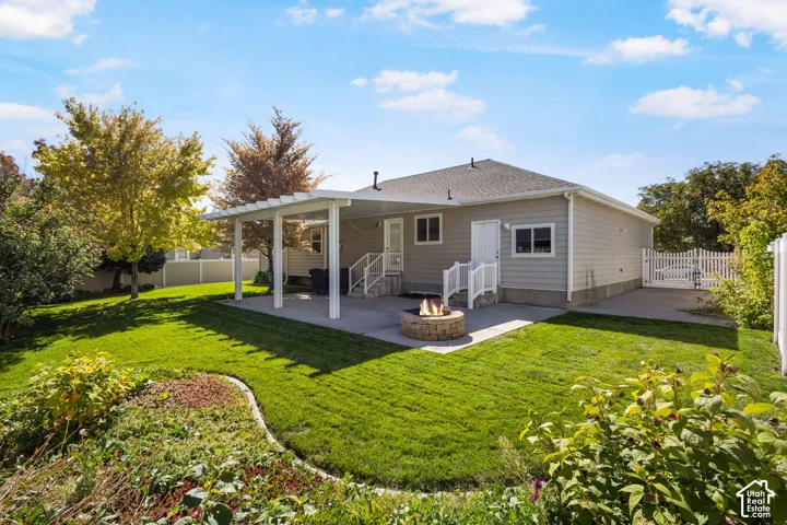 Expansive backyard with a manicured lawn, concrete patio, pergola, and built-in fire pit