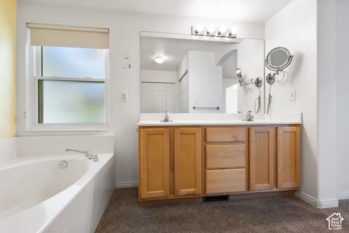 Dual vanity with light wood-finish cabinetry, white countertop, and integrated sinks