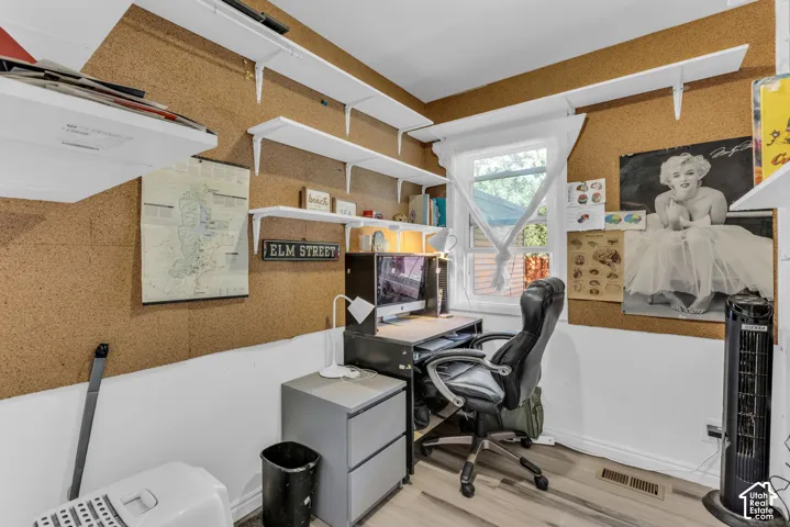 Room featuring cork board walls, white shelving, a window, and wood-finish flooring