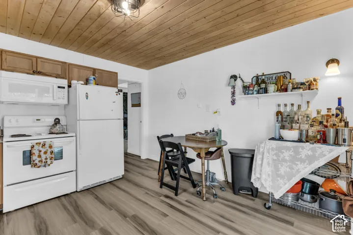 Wood-finish plank flooring, white appliances, and warm wood cabinetry