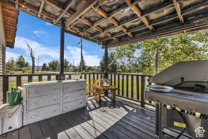 Covered porch featuring a wood-finish deck and exposed wood ceiling joists
