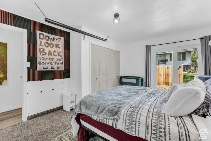 Sliding glass door, textured wall paneling, flush-mount ceiling light, and carpeted flooring