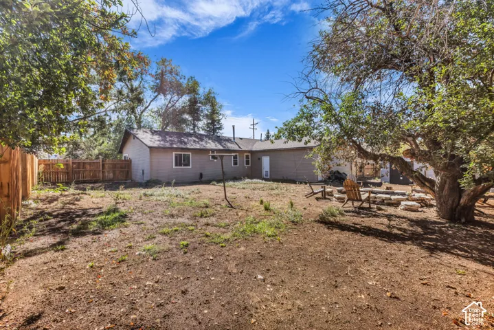 Rear exterior featuring a neutral-toned facade, multiple windows, and a wood privacy fence