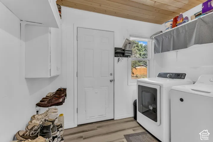 Hardwood plank ceiling, white paneled door, built-in white cabinetry, window with natural light, and wood-finish flooring