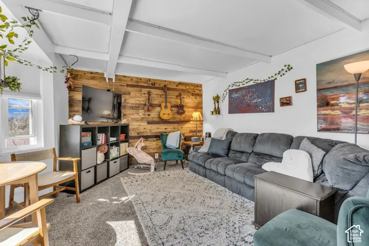Exposed ceiling beams, wood-finish accent wall, and a large window with natural light