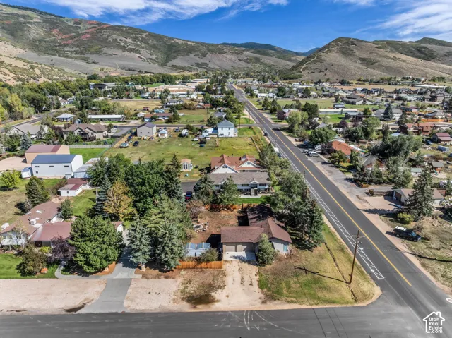 Expansive mountain backdrop, established neighborhood setting, paved road frontage, and varied tree canopy