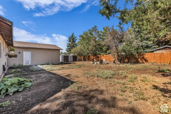 Expansive backyard with a wood privacy fence, multiple storage sheds, and mature trees
