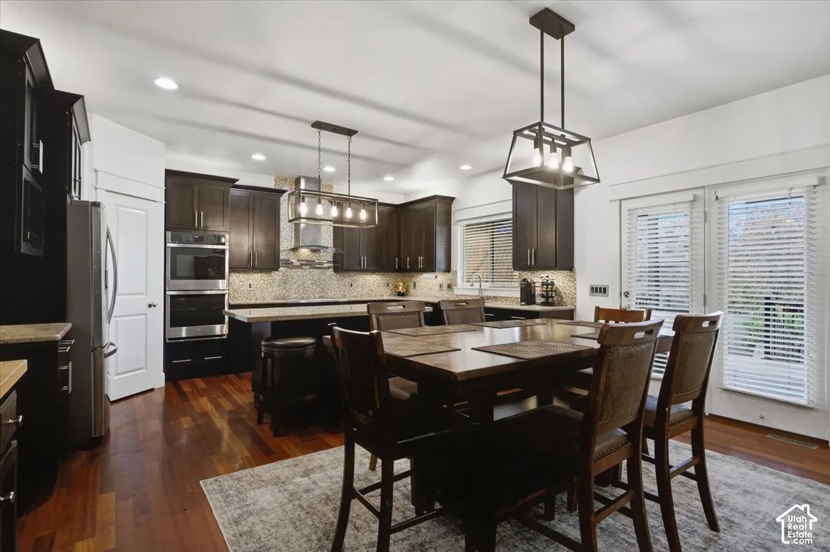 Rich wood-finish flooring, dark wood cabinetry, and stainless steel double ovens