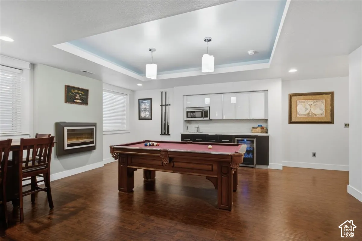 Recessed lighting and pendant fixtures illuminate a tray ceiling