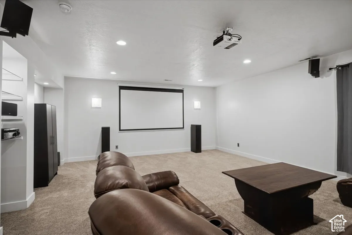 Integrated projection screen, ceiling-mounted projector, recessed lighting, wall-mounted speakers, and carpeted flooring