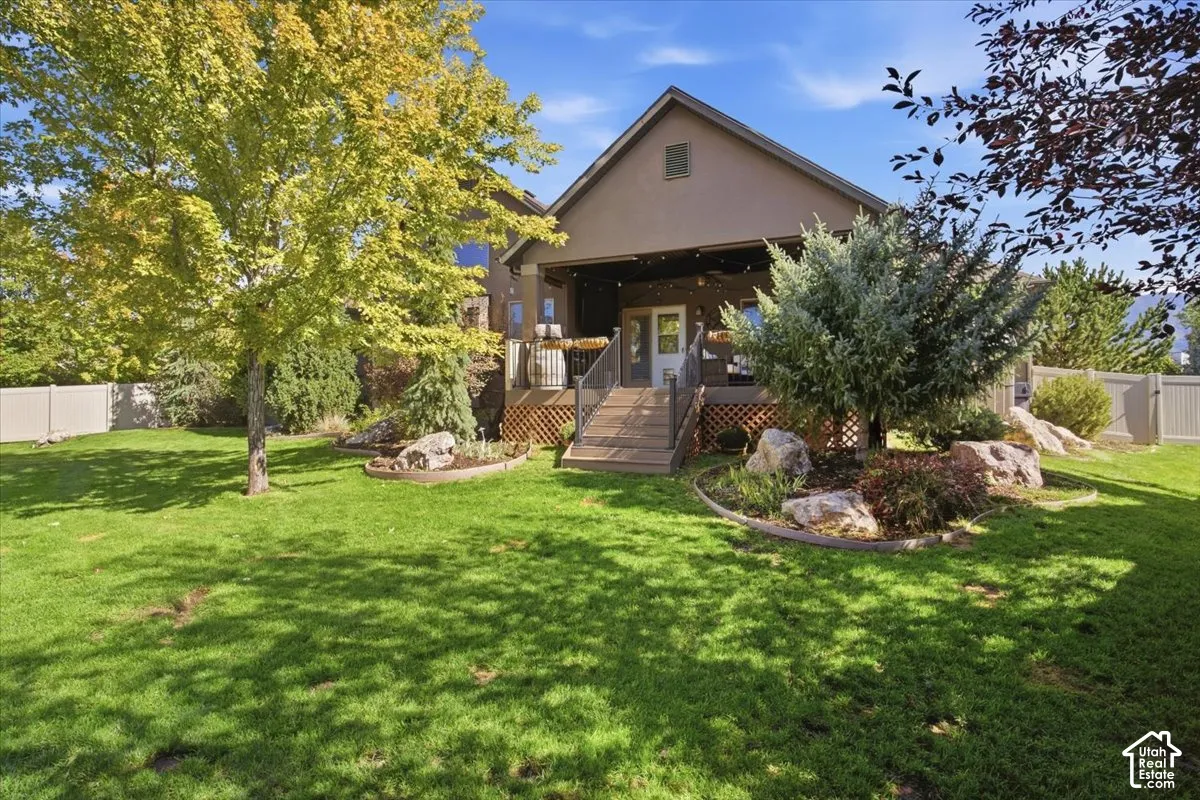 Expansive backyard with a covered patio, wood-finish deck, and decorative rock landscaping