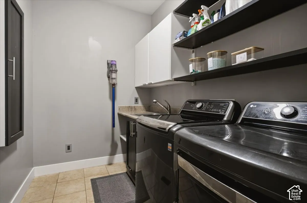 Laundry space with tile flooring, built-in cabinetry, open shelving, and a countertop with an integrated sink