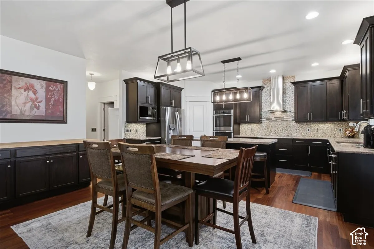 Wood-finish flooring, dark wood cabinetry, stainless steel appliances, and pendant lighting