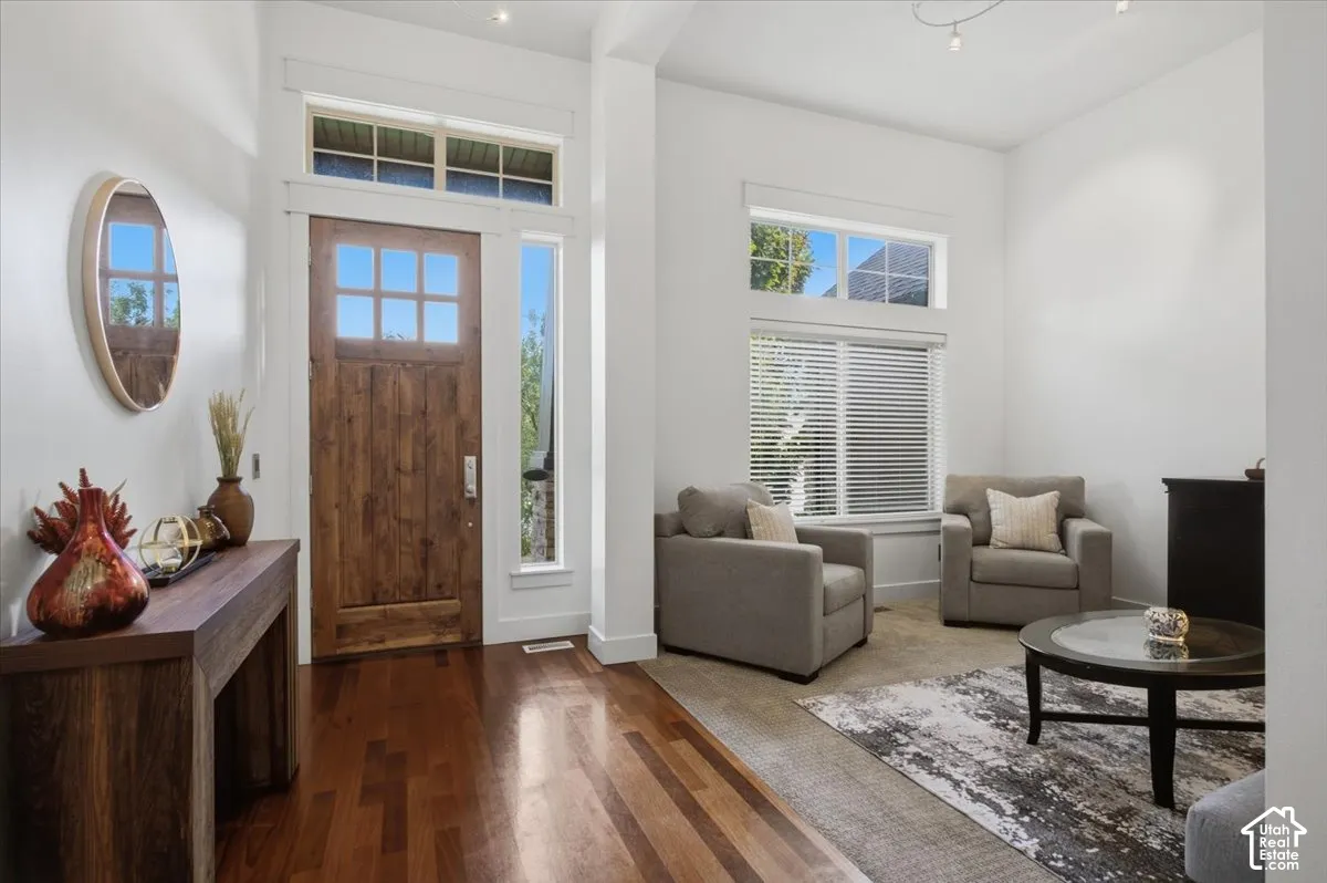 Wood-finish flooring, solid wood entry door with glass panels, transom windows, and white trim
