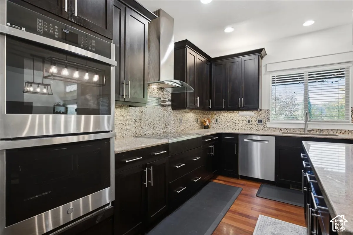 Dark wood-finish cabinetry, built-in stainless steel appliances, mosaic tile backsplash, and light-toned countertops