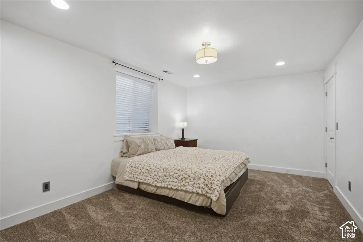 Recessed ceiling lighting, ceiling-mounted light fixture, window with blinds, panel door, and brown carpeting