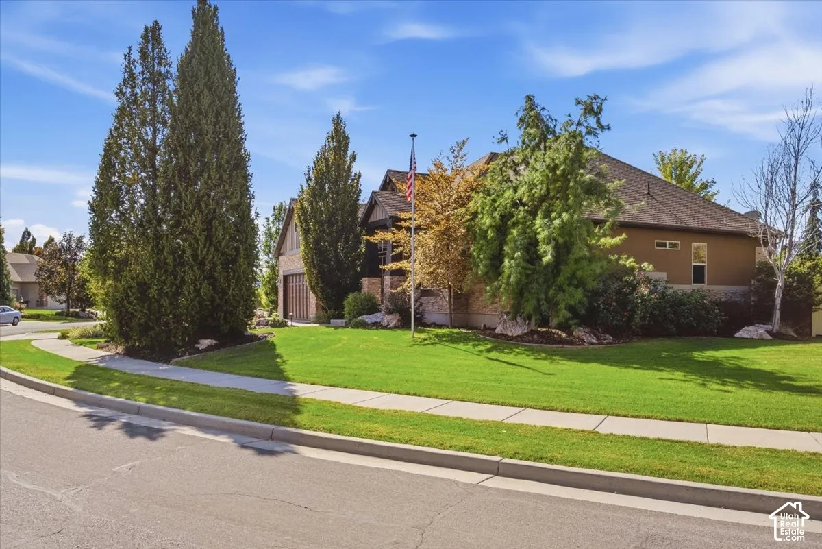Siding with stone accents, a gabled roof, an attached garage, a paved driveway, and manicured landscaping